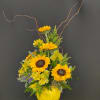 Sunflower arrangement in a yellow smiley-face vase with curly branches