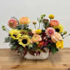 Mixed bouquet of sunflowers, roses, and dahlias in a white ceramic vase
