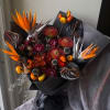 Bouquet with orange bird-of-paradise and dark tropical blooms wrapped in black paper