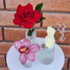 Three small floral arrangements with roses and orchids on a white table.
