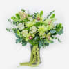 Green and white floral arrangement in a glass vase with orchids and roses