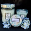 Three decorative candles with blue hydrangea blooms on a black background