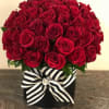 Red rose arrangement in a black box with a striped ribbon
