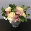 Cream roses and pink orchids arranged in a dotted glass vase
