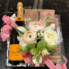 Gift basket with flowers, champagne, macarons, and candy in a clear tray