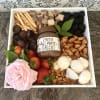 Gift tray with fruit, chocolates, crackers, nuts, and a pink rose