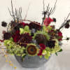 Mixed floral arrangement in a gray bowl with dark branches and red blooms