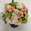 Bouquet of peach and white roses with green hydrangeas in a black vase