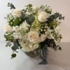 White rose bouquet in a clear glass vase with eucalyptus and small white filler flowers