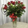 Red roses in a tall glass vase with a red ribbon