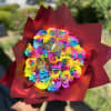 Rainbow bouquet of roses wrapped in burgundy paper with butterfly picks