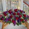 Large arrangement of red roses and purple flowers on a wooden table