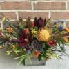 Mixed floral arrangement in a wooden box with orange and burgundy blooms