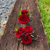 Red rose corsage and boutonniere set on a wooden surface