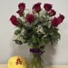 Bouquet of red roses in a glass vase with a yellow cap beside it.
