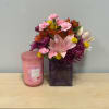 Mixed bouquet in a purple vase beside a pink candle jar