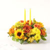 Yellow and orange flower arrangement with two tall candles