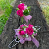 Pink rose corsage and boutonniere with ribbon on a wooden bench