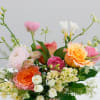 Mixed bouquet of roses, ranunculus, and white blooms in a rustic container