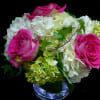 Compact arrangement of hot pink roses and white hydrangeas in a clear glass vase