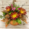 A cheerful orange ceramic pumpkin filled with flowers that evoke warmth and