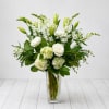 White flowers arranged in a clear glass vase with green accents