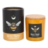 Two scented candles in amber jars with bee labels and cork lids