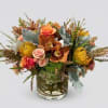Mixed bouquet of orange, pink, and yellow flowers in a clear glass vase