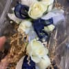 White rose corsage with navy ribbon in clear packaging