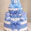 Blue teddy bear atop a diaper cake with striped ribbons and baby socks