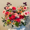 Mixed pink and peach floral arrangement in a white basket vase