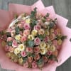 Large bouquet of pink, peach, and cream roses wrapped in pink paper
