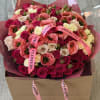 Large bouquet of pink, coral, and cream roses in a box with pink ribbons
