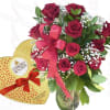Bouquet of red roses in a glass vase beside a heart-shaped chocolate box