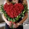 Heart-shaped bouquet of red roses with green foliage and a red ribbon