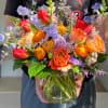 Colorful bouquet of tulips, roses, and ranunculus in a glass vase