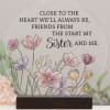 Round memorial plaque with floral illustration and sister quote on a wooden stand