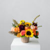Mixed bouquet with sunflowers, roses, and a small pumpkin in a ribbed vase