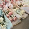 Several pastel rose bouquets wrapped in paper with baby's breath