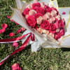 Bouquet of pink and blush roses wrapped in white paper with gold trim