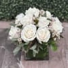 White rose bouquet in a square glass vase with small pink blossoms