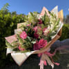 Bouquet of pink roses and white snapdragons wrapped in pastel paper