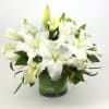 White lilies and calla lilies arranged in a glass vase