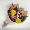 Mixed bouquet of colorful flowers wrapped in brown paper with a birthday topper