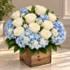 White roses and blue hydrangeas arranged in a wooden box