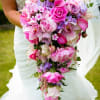 Bride holding a cascading bouquet of pink and purple flowers