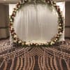 Large floral arch with red and white roses in front of a white backdrop