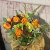 Orange roses and green orchids arranged in a glass vase