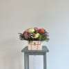 Mixed bouquet in a pink handbag-style container on a small table
