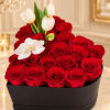 Red roses arranged in a black box with white tulips and an orchid bloom